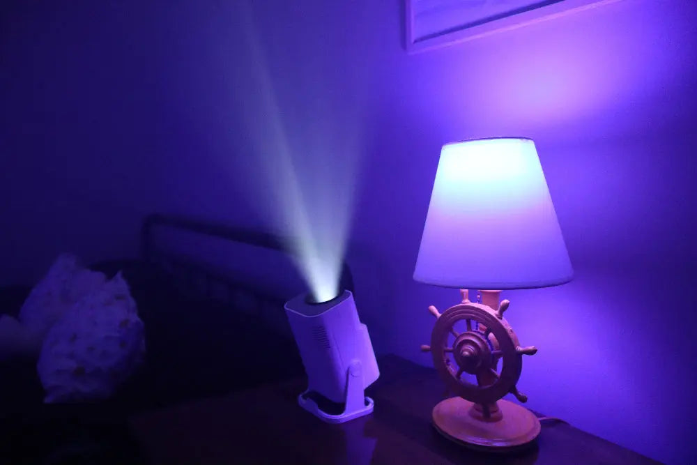 Ozmotic Learning projector casting a beam of light onto the ceiling in a dimly lit bedroom with purple ambiance.